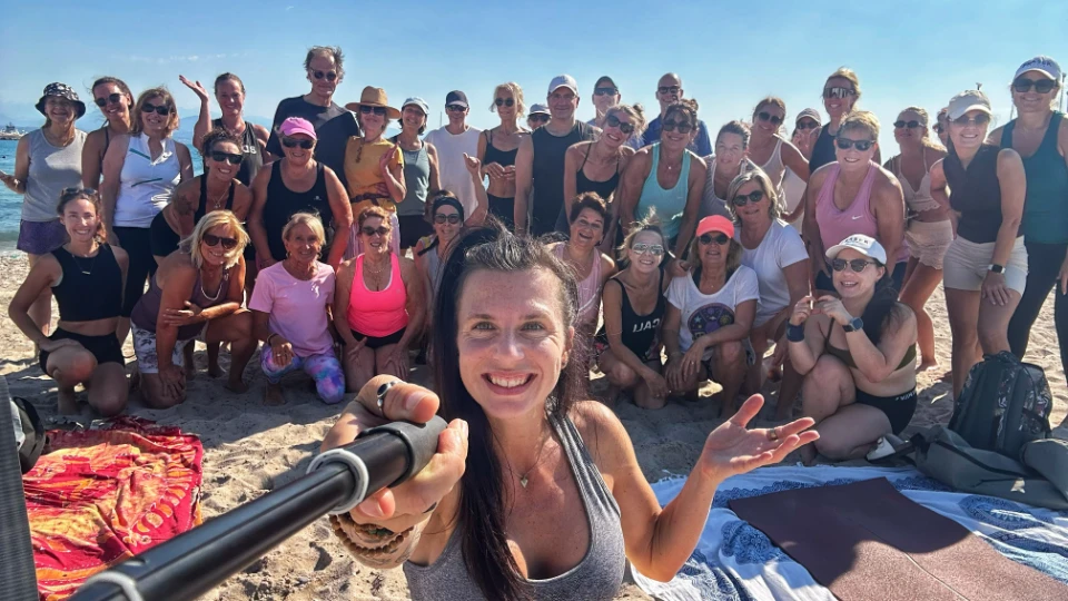 Un groupe large et souriant de femmes profite d'une séance de yoga sur la plage ensoleillée.